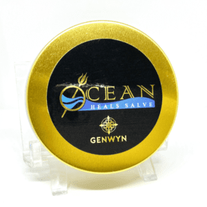 A gold and black tin of ocean brand salve.