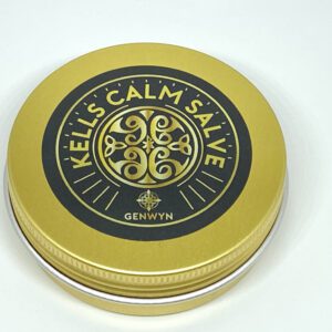 A gold tin of calm salve sitting on top of a table.