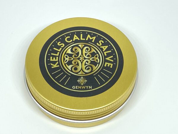 A gold tin of calm salve sitting on top of a table.