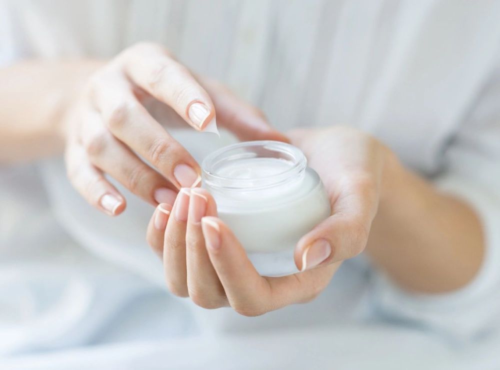 A woman holding a jar of cream in her hands.